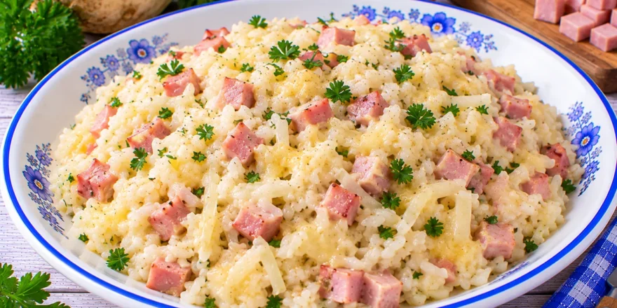 Cremiger Selleriereis mit Sellerie, Schinkenwürfeln und geschmolzenem Käse.