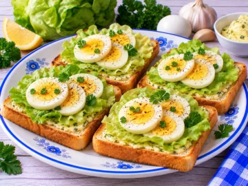 Gerösteter Toast mit Knoblauchbutter, frischem Kopfsalat und hartgekochten Eischeiben.