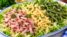 Dreifarbensalat mit Schinkenstreifen, Käse, grünen Bohnen und frischem Blattsalat.