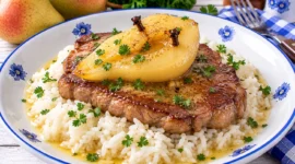 Gebratenes Steak mit gedünsteter Birnenhälfte auf Reis angerichtet.