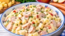 Cremiger Wiener Käsesalat mit Käsewürfeln, Wiener Würstchen und Apfelstücken.