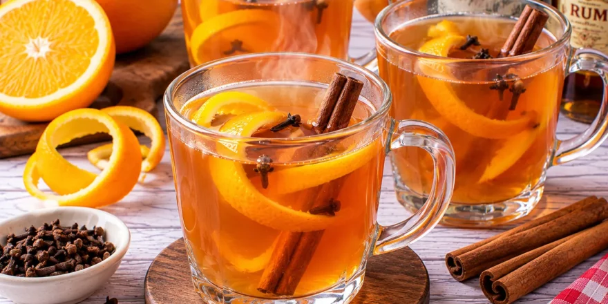 Heißer Tee-Orangen-Grog mit Orangenschale, Zimt, Nelken, Wermut und Rum.