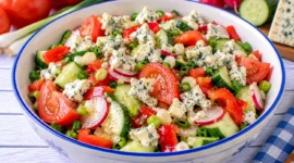 Bunter Gemüsesalat mit Tomaten, Paprika, Gurke, Radieschen und zerbröseltem Roquefortkäse.