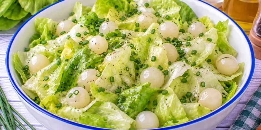 Frischer Kopfsalat mit ganzen Einmachzwiebeln und Schnittlauch-Vinaigrette.