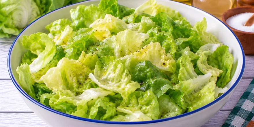 Frischer grüner Kopfsalat mit einem einfachen Dressing aus Öl, Essig, Zucker und Salz.
