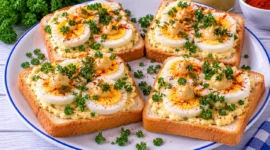 Belegte Weißbrotschnitten mit hartgekochten Eiern, Senf, Petersilie und Paprika.
