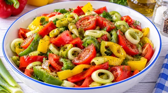 Bunter Gemüsepaprikasalat mit Paprika, Peperoni, Tomaten und Porreeringen.