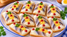 Zehn Heringsandwiches mit gehacktem Eigelb, Eiweiß und kleinen Tomatenmarktupfen.