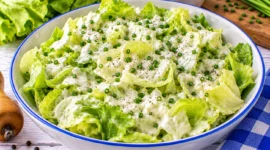 Frischer Kopfsalat mit cremigem Sahnedressing und fein geschnittenem Schnittlauch.