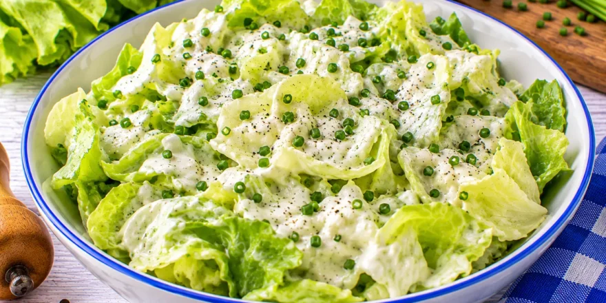 Frischer Kopfsalat mit cremigem Sahnedressing und fein geschnittenem Schnittlauch.