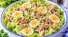 Frischer Kopfsalat mit Thunfischstücken, Eierscheiben und fein geschnittenen Zwiebeln.