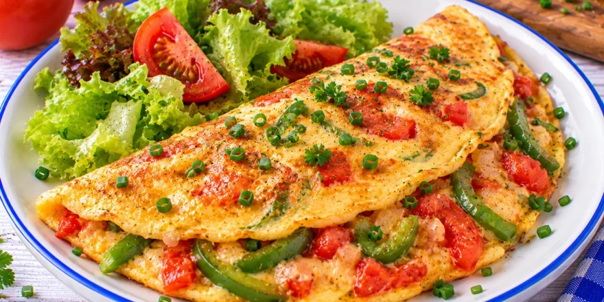 Goldgelbes Paprika-Omelett mit grünen Paprikastreifen, Tomaten und frischem Schnittlauch.