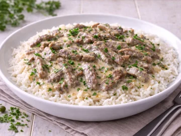 Majoranfleisch aus Rindfleischstreifen in Majoransoße mit saurer Sahne auf weißem Teller mit Reis