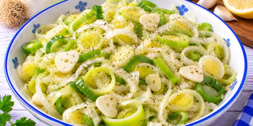Frischer Porreesalat mit feinen Porreeringen, Knoblauchscheiben und Zitronendressing.