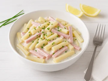 Spargelsalat mit Schinken in einer weißen Schüssel mit cremiger Soße, Schnittlauch und heller Tischdekoration