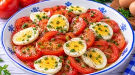 Tomatensalat mit hartgekochten Eierscheiben, Schnittlauch und Zitronendressing.