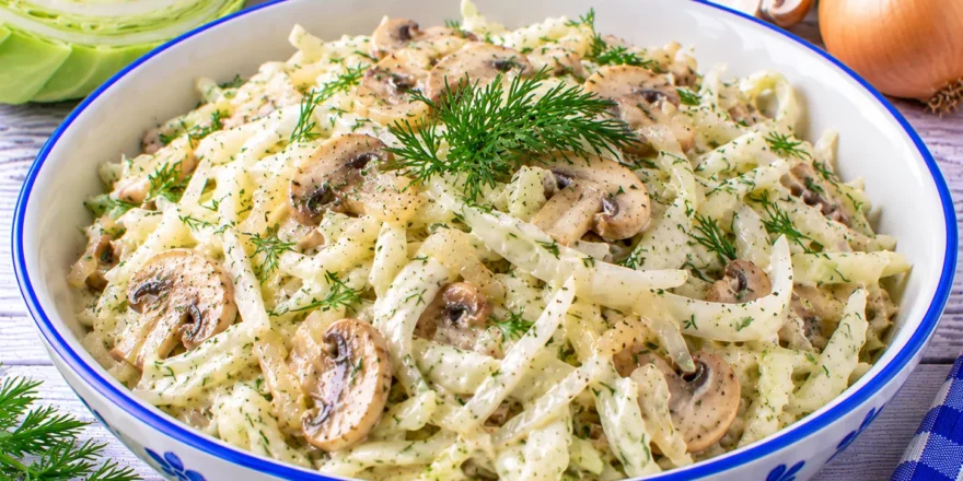 Cremiger Weißkohlsalat mit Champignons, Zwiebeln, Joghurt und frischem Dill.