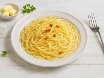 Spaghetti auf weißem Teller mit Butter und Speckwürfeln, serviert auf hellem Holztisch